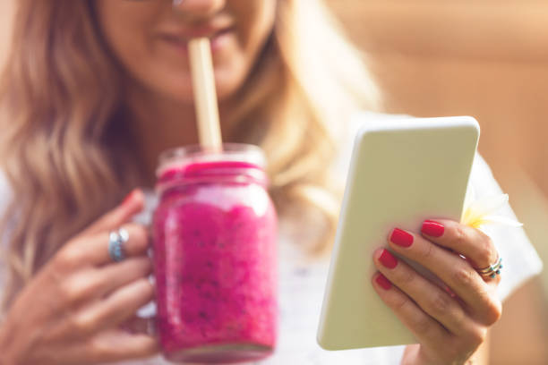 istock Cute woman using cellphone while drinking smoothie outdoors. 959114908