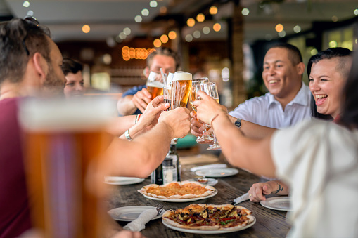 Multi-ethnic friends toasting drinks at table. Happy men and women are spending leisure time together. They are enjoying in restaurant.