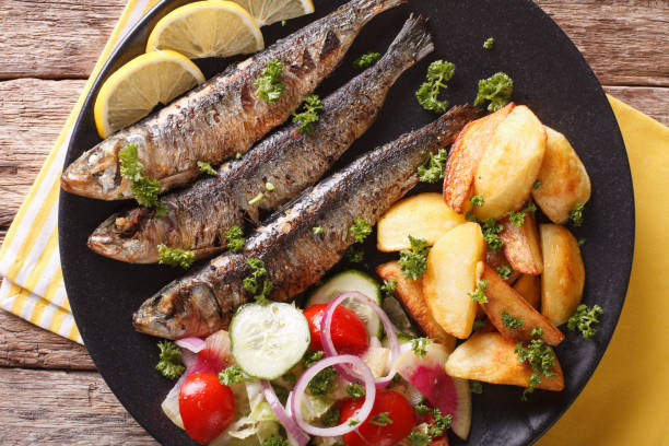 istock Fried sardines with roasted potatoes and fresh salad closeup. horizontal top view 959115830