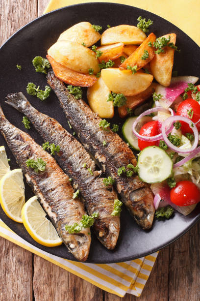 istock Fried sardines with roasted potatoes and fresh salad closeup. vertical top view 959116216