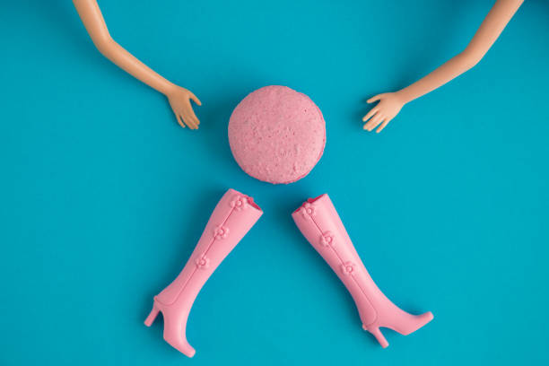 Macaroon with doll hands and boots against blue background minimal fashion and food creative concept.