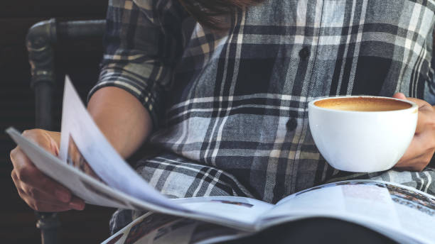 istock Closeup image of a woman reading a book while drinking coffee in modern cafe 959119856