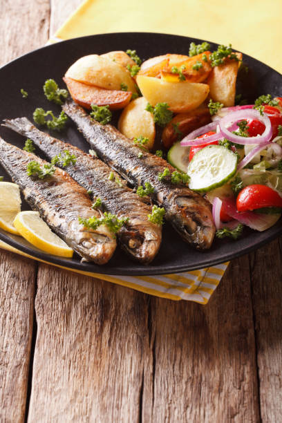 istock Grilled sardines with roasted potatoes and fresh salad closeup. vertical 959120230