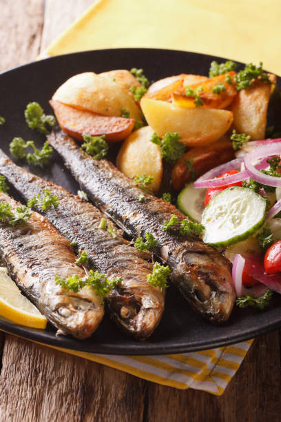 istock Grilled sardines with roasted potatoes and fresh vegetable salad close-up. vertical 959120264