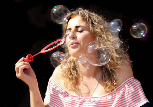 istock beautiful woman curly hair blowing soap bubbles 959134480