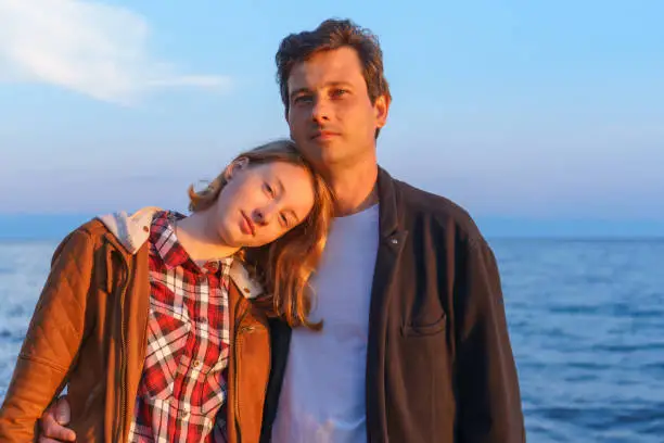 Portraits of father and daughter in the summer at sunset on the shore of lake Baikal