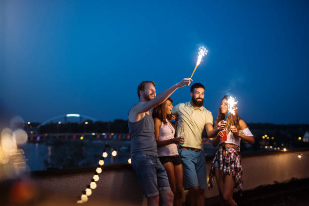 istock Friends enjoying a rooftop party and dancing with sparklers 959141712