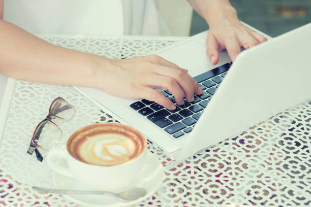 istock Woman drinking coffee and using a laptop on a white table. 959149094