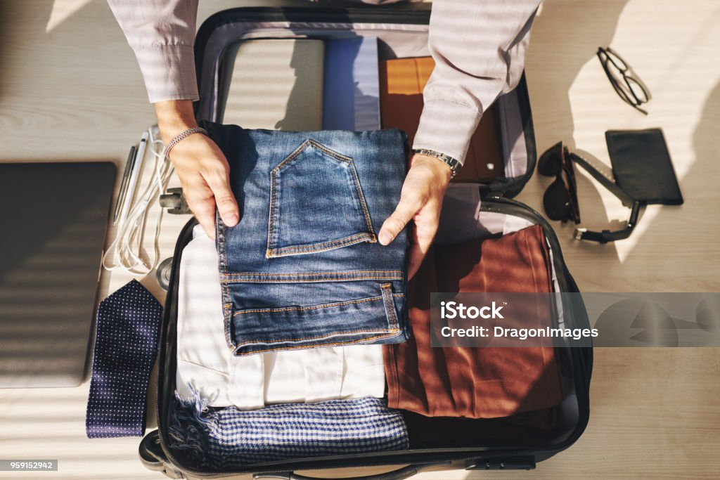 Packed clothes Close-up of man packing clothes in luggage for a trip Packing Stock Photo