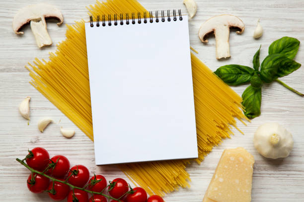 istock Different ingredients for cooking pasta with notebook on a white wooden background. Top view. Flat lay. From above. Space for text. 959153672