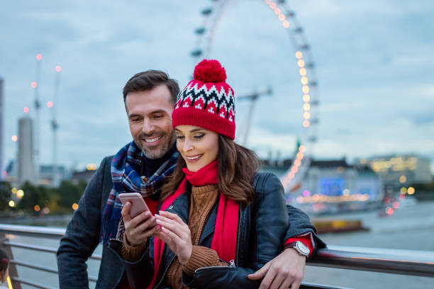 istock Couple using smart phone against ferris wheel in london 959156548
