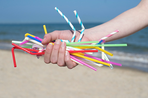 Close Up de la mano con Pajitas de plástico contaminan playa photo