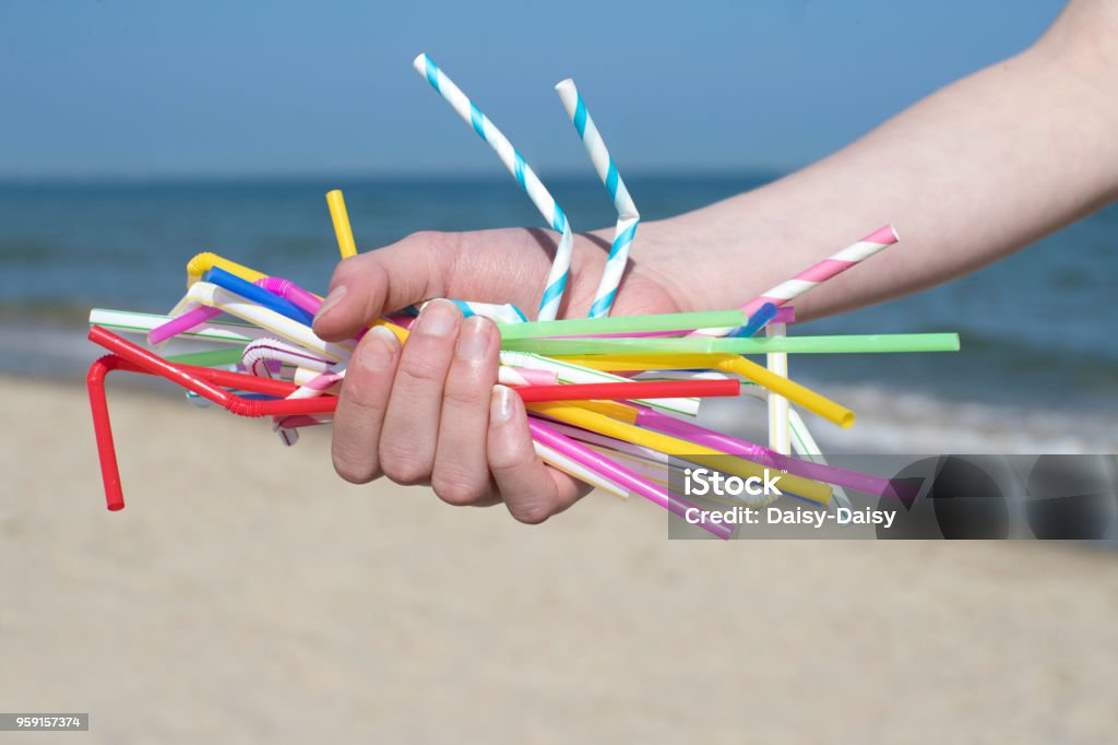 Gros plan de main tenant les pailles en plastique polluant Beach - Photo de Paille pour boire libre de droits