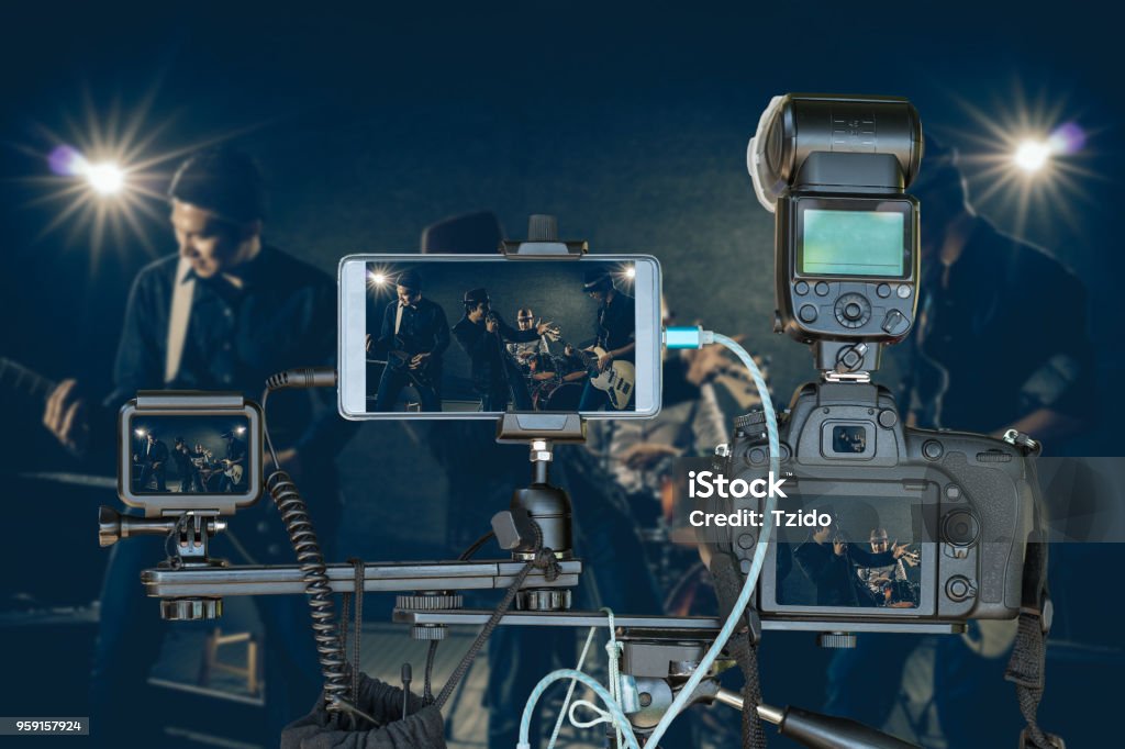 Professional set of camera with smart mobile phone and action camera on tripod over Musician band holding the microphone singing a song and playing music instrument,Live Streaming for musical concept Live Streaming Stock Photo