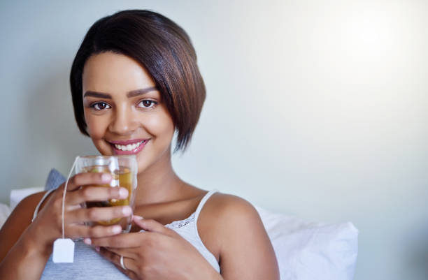 Help to protect the environnement by banning plastic straw and using paper one instead. Young adult woman holding colourful drink with paper straw. She is looking at the camera with a soft smile. horizontal headshot on white background.