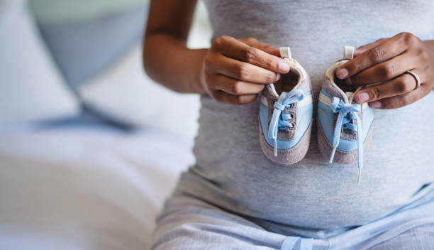 Tiny blue shoes for my tiny little bub Cropped shot of a pregnant woman holding a pair of blue baby shoes in front of her belly baby booties stock pictures, royalty-free photos & images