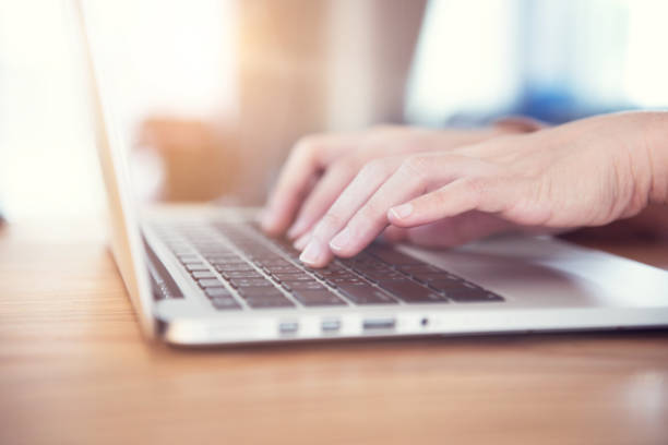 istock Woman's hands typing on a laptop on a wooden desk 959161894
