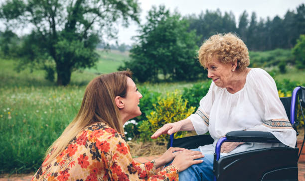 Young woman talking to elderly woman in a wheelchair Affectionate young woman talking to elderly woman in a wheelchair in the garden Dementia Care stock pictures, royalty-free photos & images