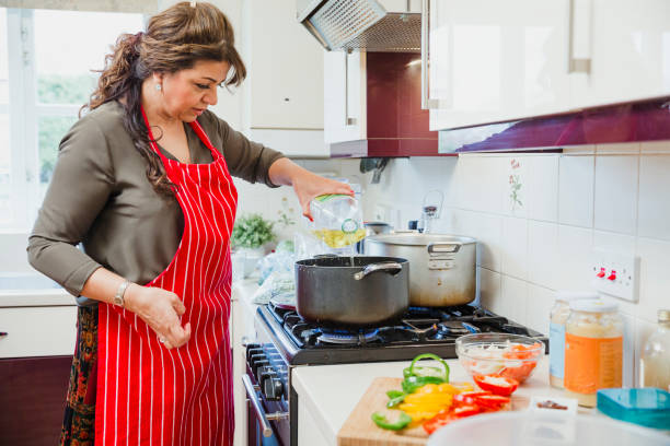 Mature Woman Adding Oil to a Pan