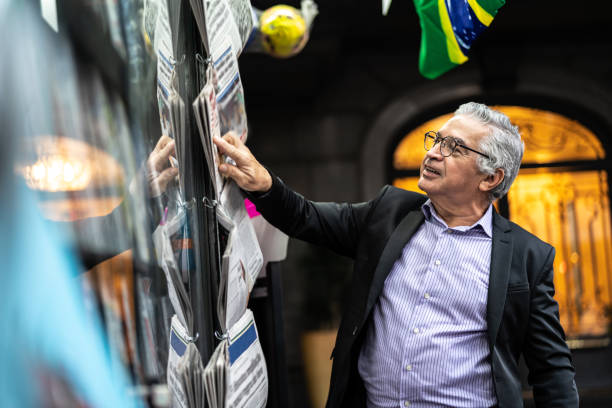 senior homme en recherchant les nouvelles au kiosque à journaux - news stand photos et images de collection