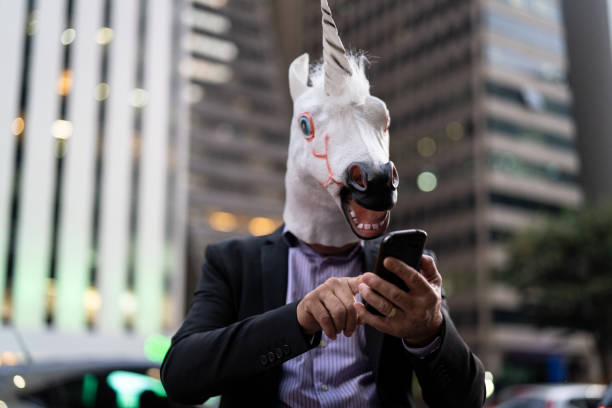 istock Business man with Unicorn Mask using mobile at city 959173756