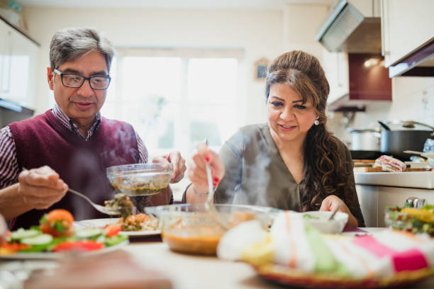 Mature Couple Enjoying Dinner at Home Mature couple are enjoying a homemade curry with salad at home. healthy indian food stock pictures, royalty-free photos & images