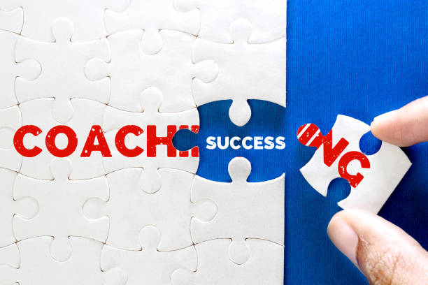 primo piano pezzo di puzzle bianco con coaching e testo di successo, concetto di business coaching portare al completamento del successo, formazione sulle risorse umane per uno sviluppo personale - leadership aspirations finance training foto e immagini stock