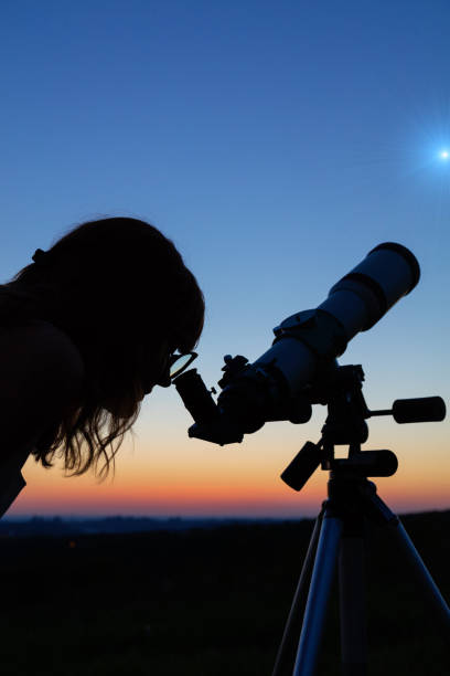 istock Woman looking at the stars with a telescope. 959179946