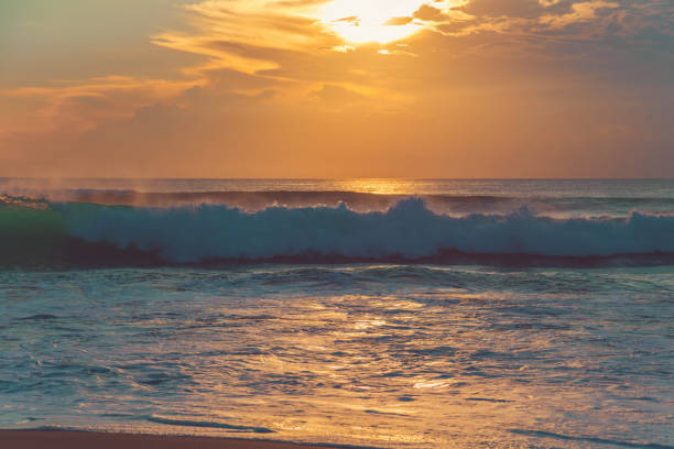 Two surfers can be seen in silhouette with sunrise on the Indian ocean close to Ballito, South Africa. A popular tourist destination.
