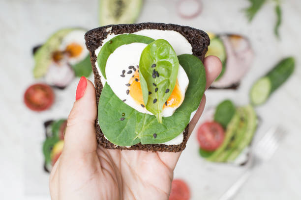 istock One sandwich with fresh summer vegetables and egg in female hand. Close up. 959181500