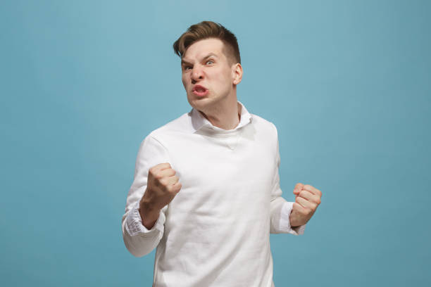 istock The young emotional angry man screaming on studio background 959184872