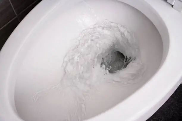 Photo of close up flushing water in toilet bowl.