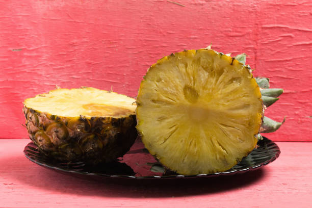 istock pineapple on dish half on pink wood. 959186610