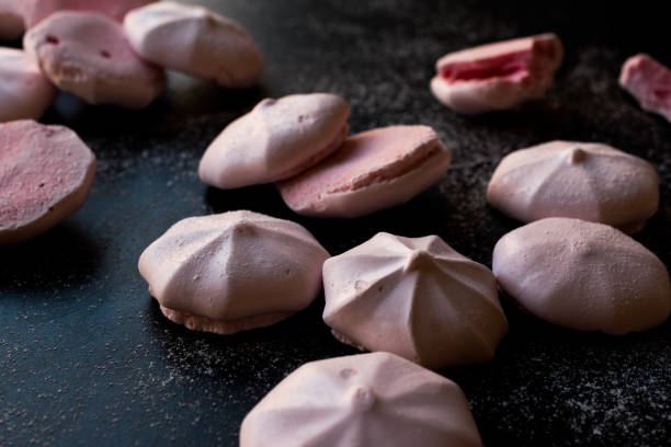 istock Pink Meringues with Powdered Sugar on Black Surface. 959186626