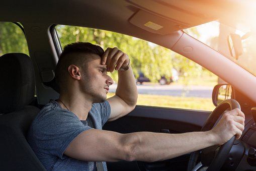 Sleepy yawning man driving car in traffic after long hour drive. Transportation sleep deprivation accident concept