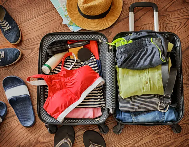 Photo of Open traveler's bag with clothing, accessories, and passport. Travel and vacations concept