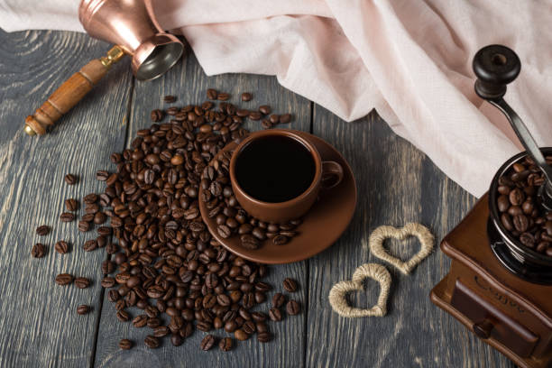 istock Cup of coffee, next to scattered coffee beans, hand mill and turka on table 959195432