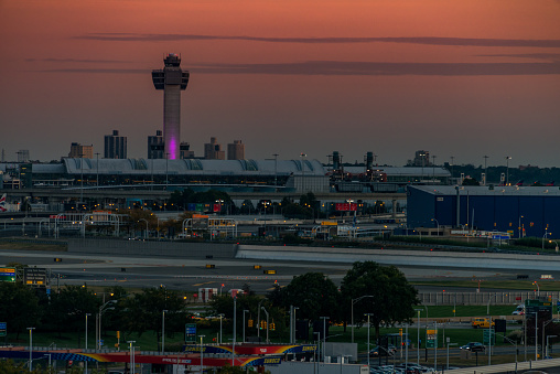 JFK airport in New York during sunset with control tower and parked airplanes