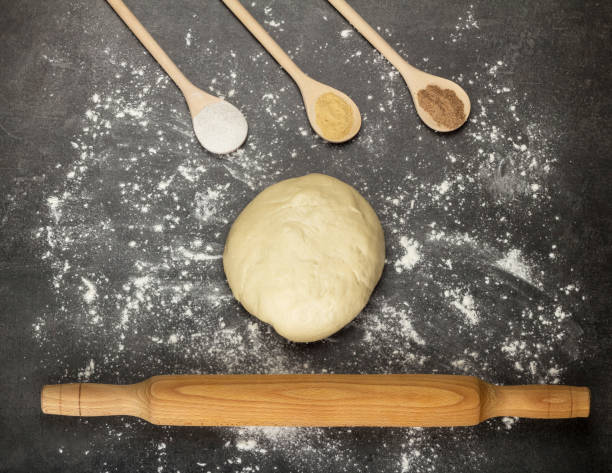 istock Wooden spoons with spices, rolling pin and piece of finished dough on work surface 959241072