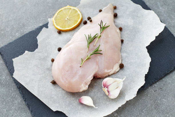 raw chicken breast with spices, garlic, lemon and rosemary on a grey stone table. - garlic chicken breast raw chicken imagens e fotografias de stock