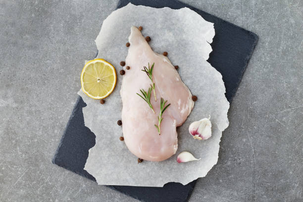 raw chicken breast with spices, garlic, lemon and rosemary on a grey stone table. top view. - garlic chicken breast raw chicken imagens e fotografias de stock