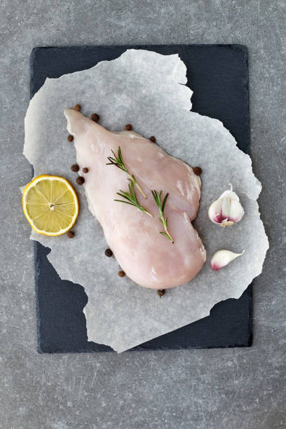 raw chicken breast with spices, garlic, lemon and rosemary on a grey stone table. top view. - garlic chicken breast raw chicken imagens e fotografias de stock