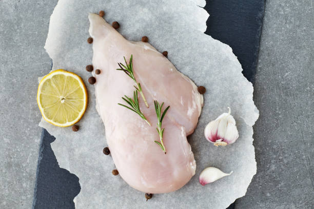 raw chicken breast with spices, garlic, lemon and rosemary on a grey stone table. top view. - garlic chicken breast raw chicken imagens e fotografias de stock