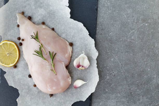 raw chicken breast with spices, garlic, lemon and rosemary on a grey stone table. top view. - garlic chicken breast raw chicken imagens e fotografias de stock