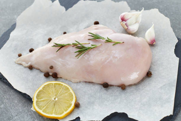 raw chicken breast with spices, garlic, lemon and rosemary on a grey stone table. - garlic chicken breast raw chicken imagens e fotografias de stock