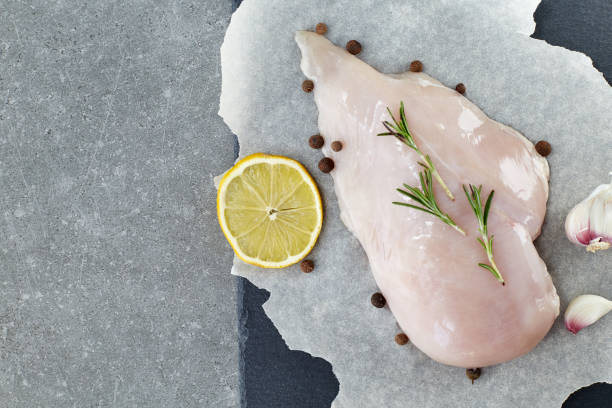 raw chicken breast with spices, garlic, lemon and rosemary on a grey stone table. top view. - garlic chicken breast raw chicken imagens e fotografias de stock