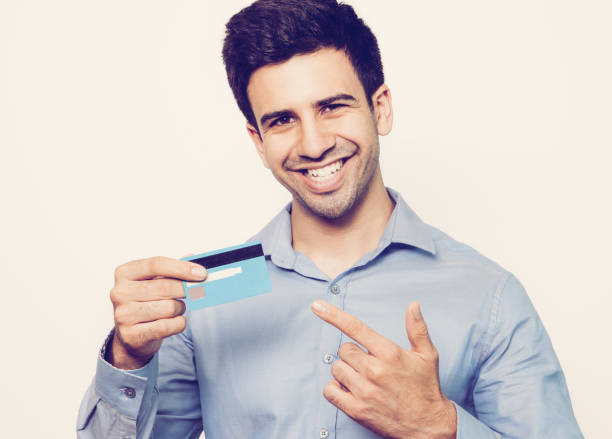 istock Successful young cardholder using convenient service for payment. Happy businessman holding credit card and pointing at this. Positive man recommending payment card. Best decision concept 959243918
