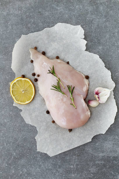 raw chicken breast with spices, garlic, lemon and rosemary on a grey stone table. top view. - garlic chicken breast raw chicken imagens e fotografias de stock