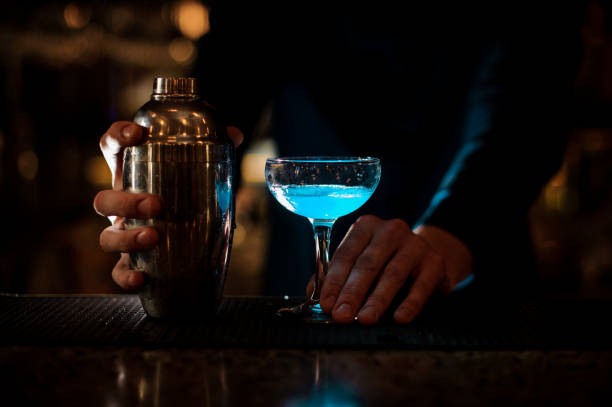 istock Man hands holding a glass with blue summer cocktail and bottle 959252958