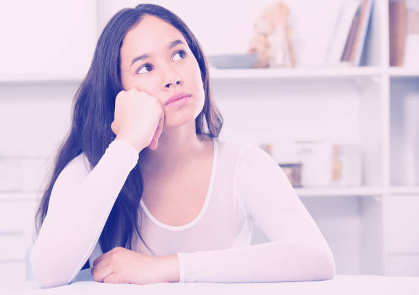 istock Gloomy girl sitting at the table 959261870